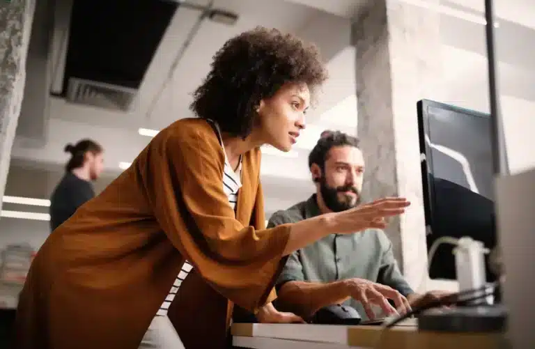 Two people working on a computer in an office.