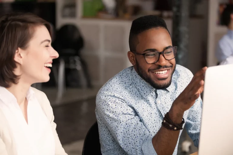 Two people sitting at a desk looking at a computer.