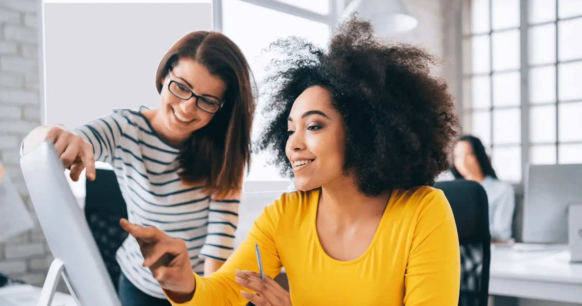 Two women in an office looking at a computer screen.