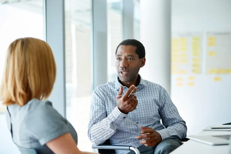 A man and woman talking in an office.