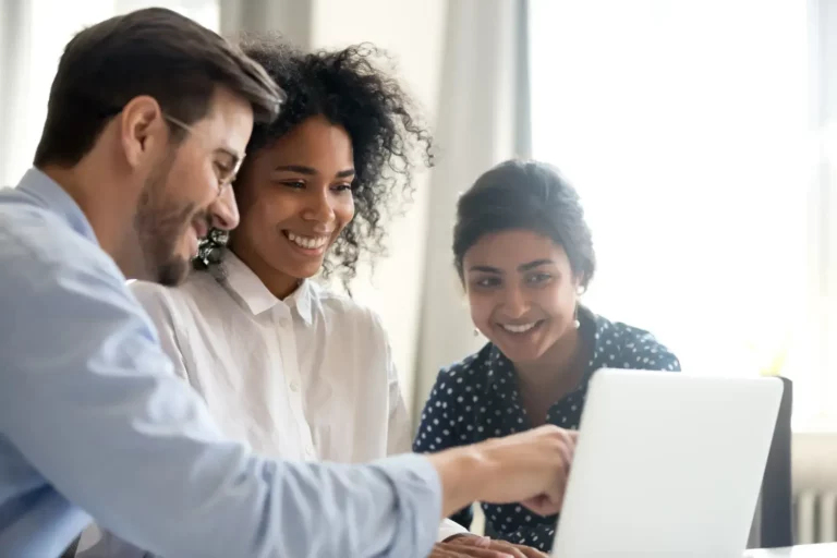 A group of people looking at a laptop.