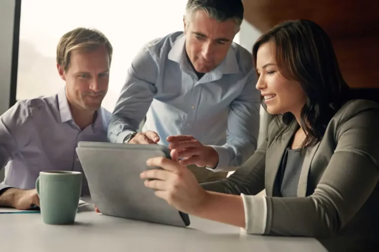 A group of business people looking at a Sage ERP system on a tablet.