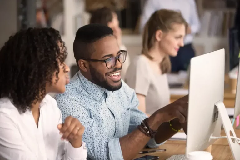 A group of people sitting at a desk looking at a computer.