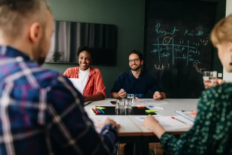 A group of people sitting around a table in a meeting room.