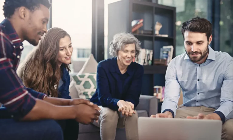 A group of people sitting on a couch looking at a laptop.