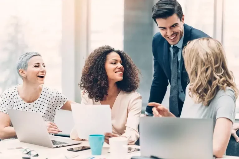 A group of business people laughing around a table.