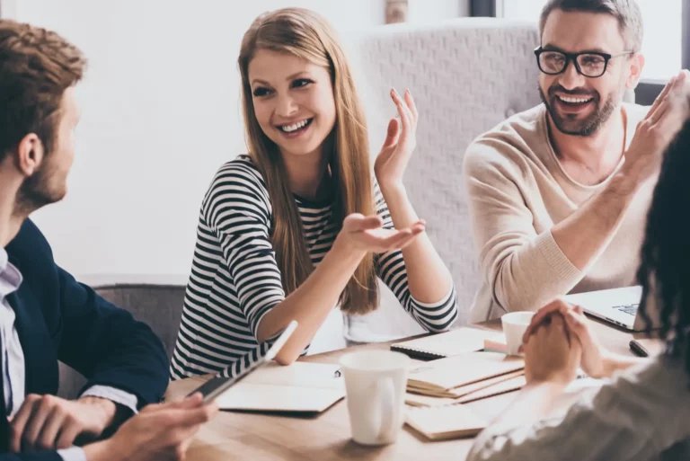 A group of people sitting around a table and clapping.