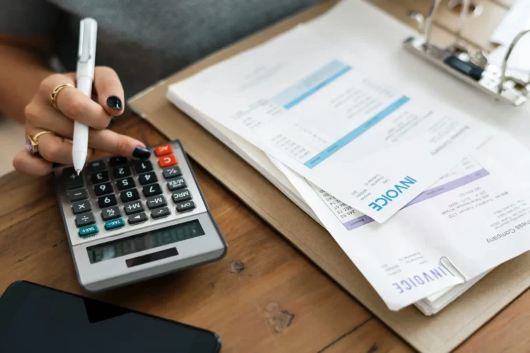 A woman is using a calculator and a pen to do her taxes.