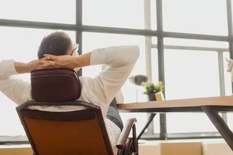 A man relaxes in a chair in front of a window.