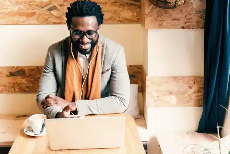 A black man sitting at a table with a laptop.