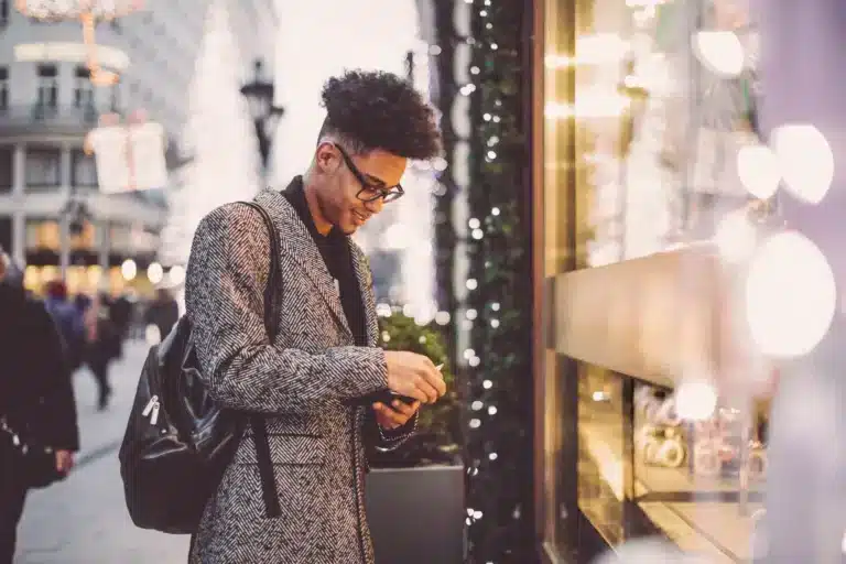 A young man looking at his phone on the street.