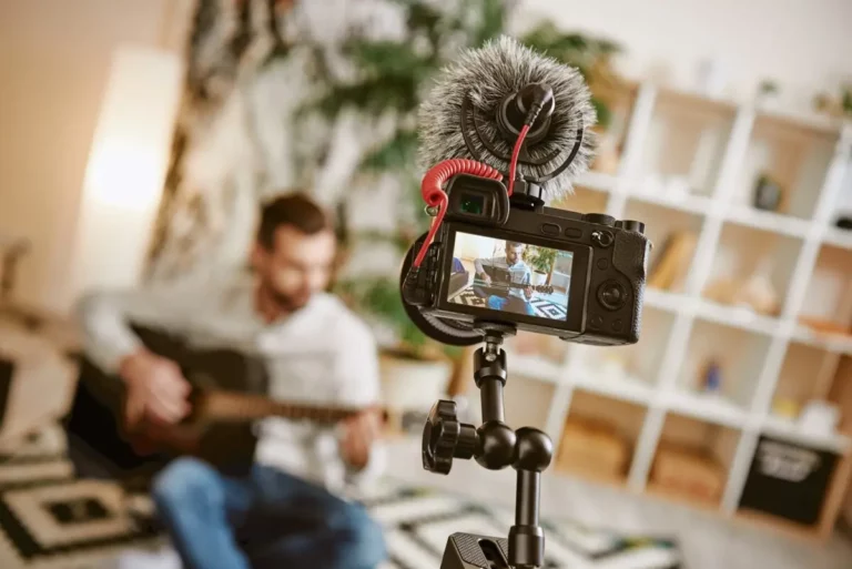 A man playing guitar in front of a video camera.