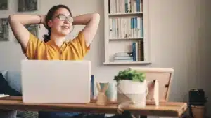 A woman is sitting at a desk with her hands raised in the air.