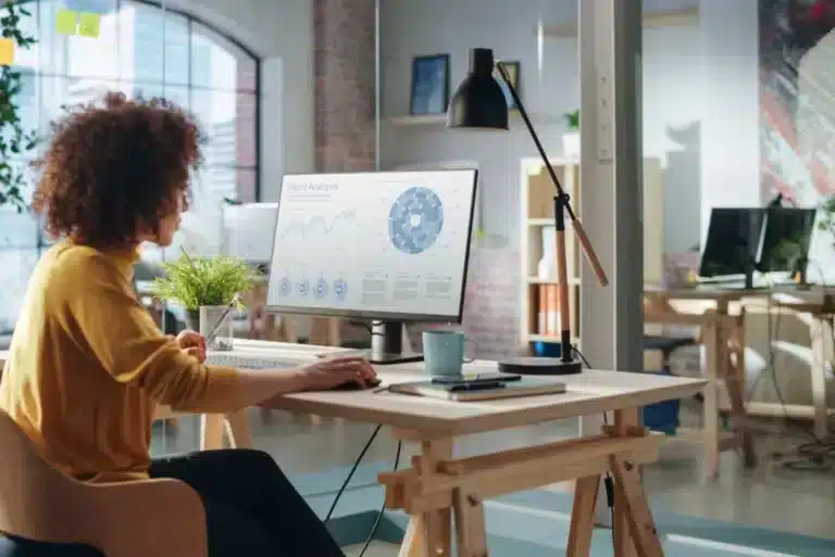 A woman is sitting at a desk and working on a computer.