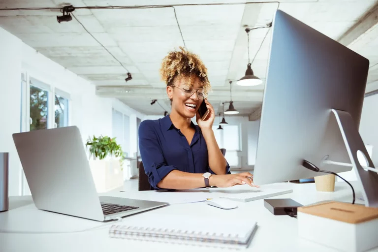 A woman talking on the phone while sitting in front of a computer.