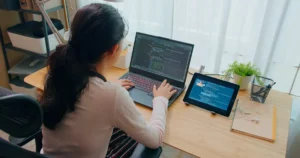 A woman sitting at a desk with a laptop and a tablet.